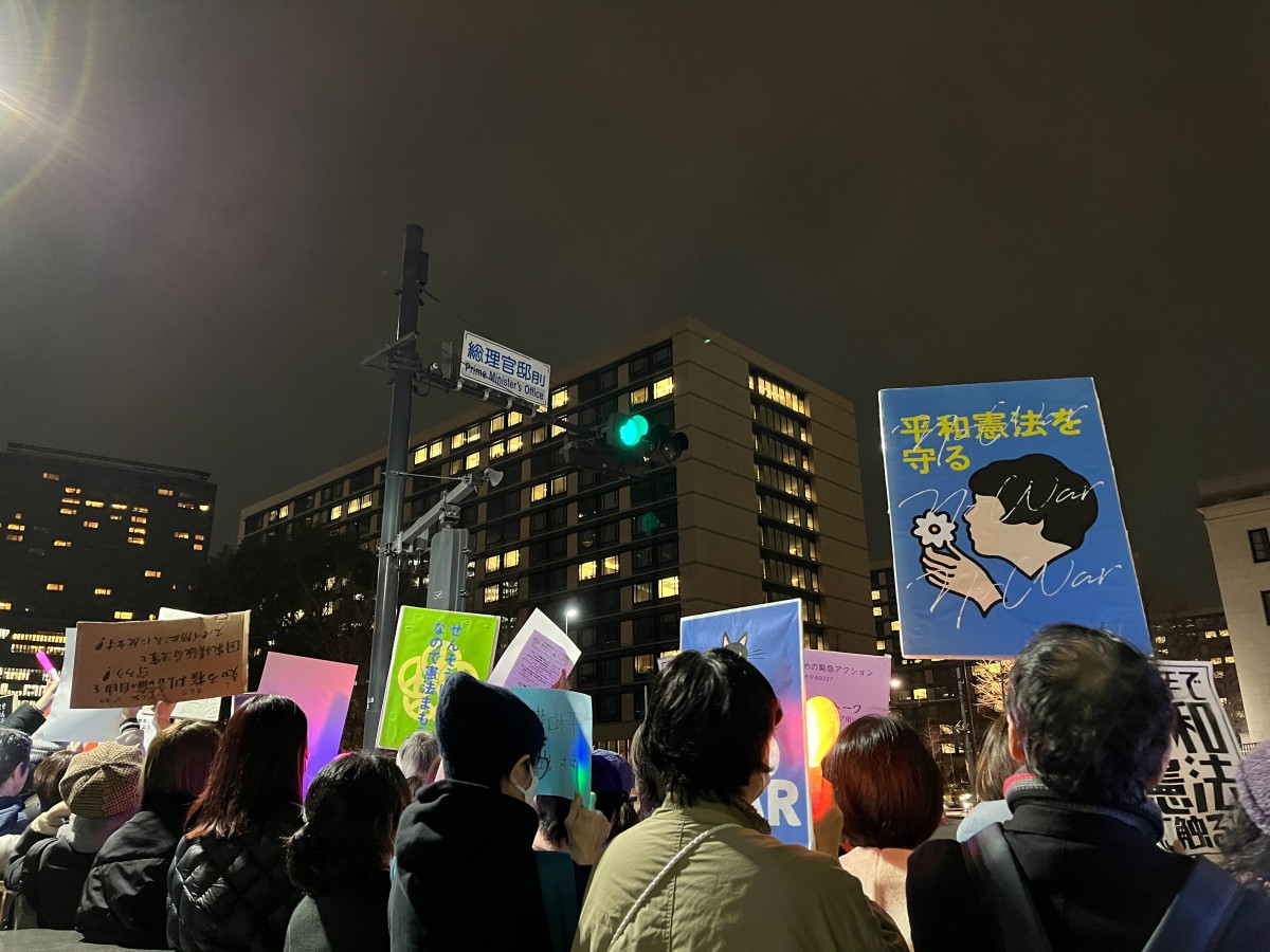 参加したデモの様子。夜、「総理官邸前」という標識のある交差点の下。プラカードなどを掲げる人たちの後ろ姿。