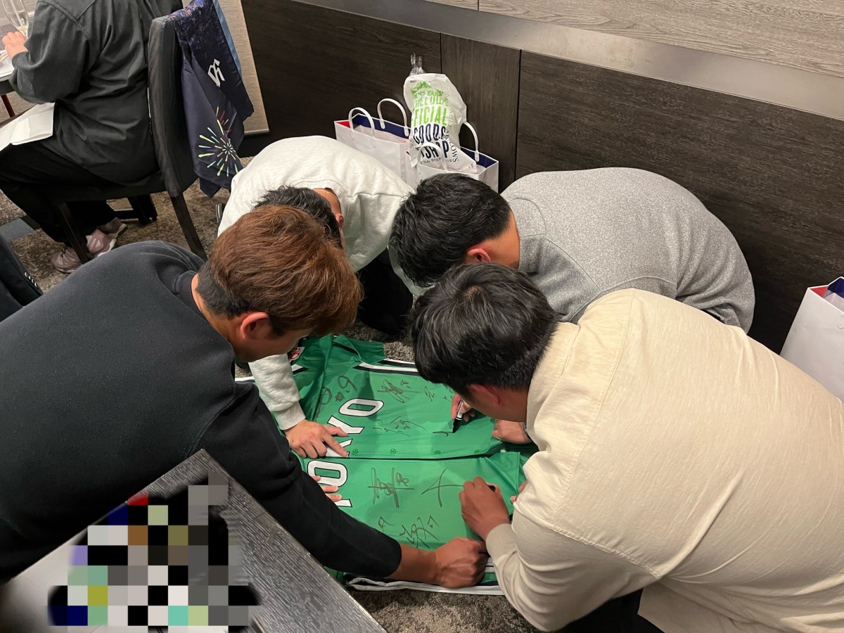 奥川、丸山選手がユニフォームを引っ張り、荘司、塩見選手がサインを書いているところ