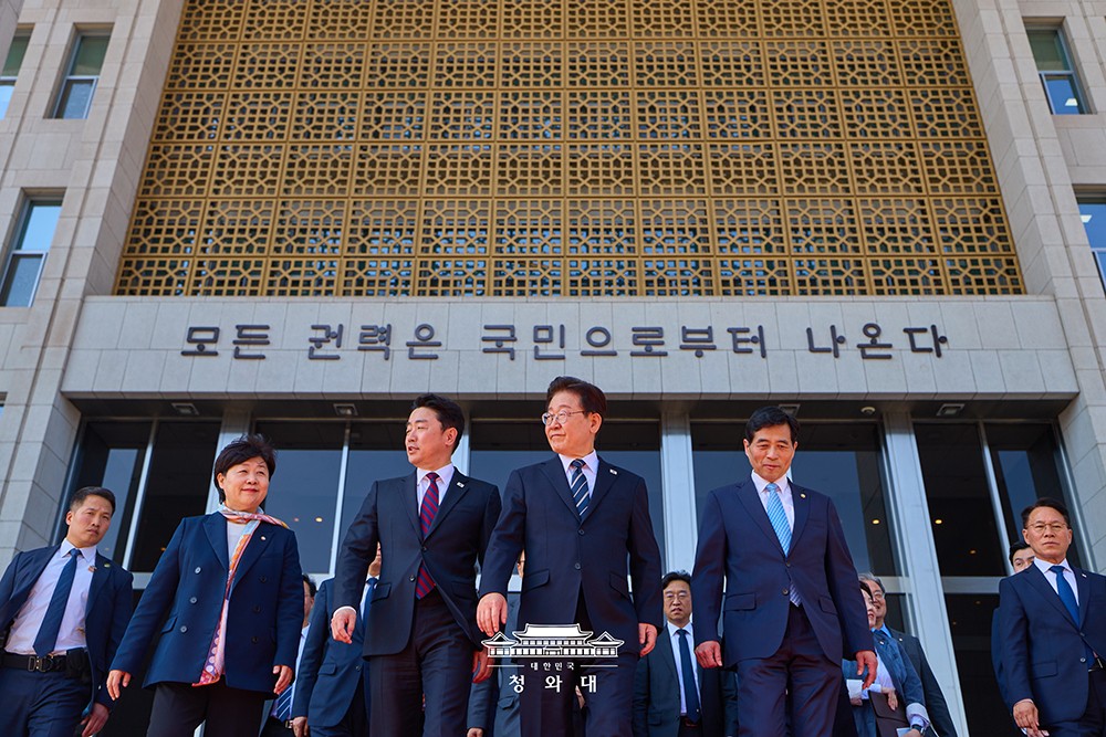 2日、国会を訪れた際に「すべての権力は国民から生じる」という文句の前で写真を撮る李在明大統領。いかにもな演出ですが、韓国社会の今をうつす断面の一つでもあります。ここは戒厳軍が押し寄せた24年12月には、憲政を守る最前線でした。青瓦台提供。