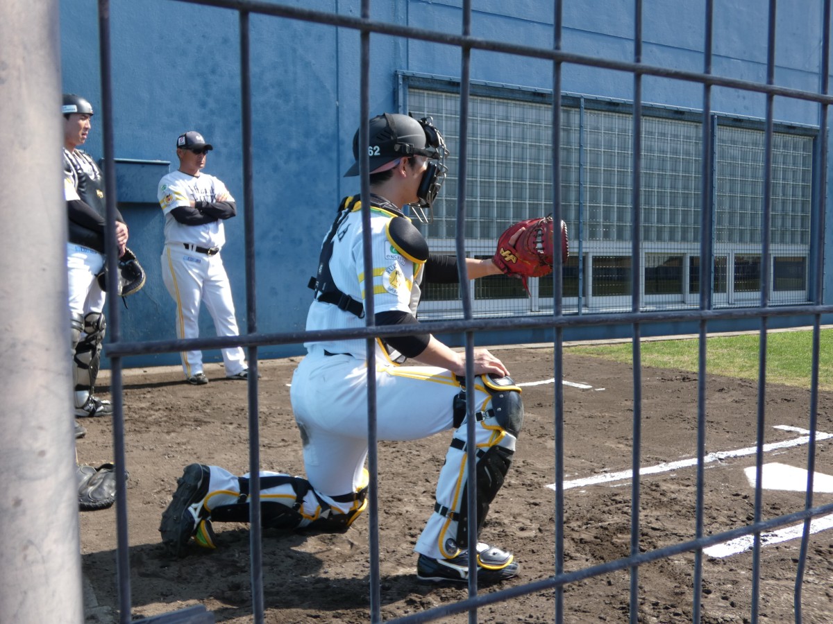 ブルペンで大関投手の投球を受ける様子