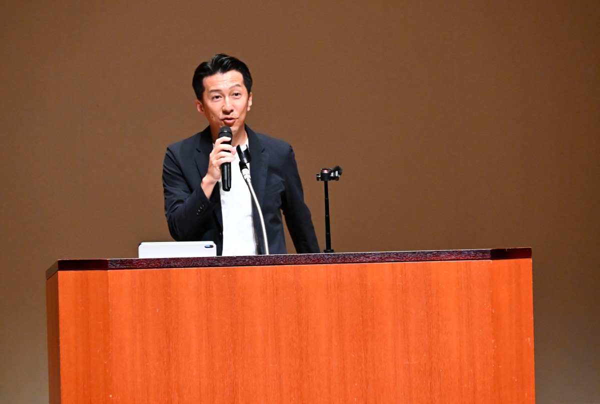 （講演する古賀真）
