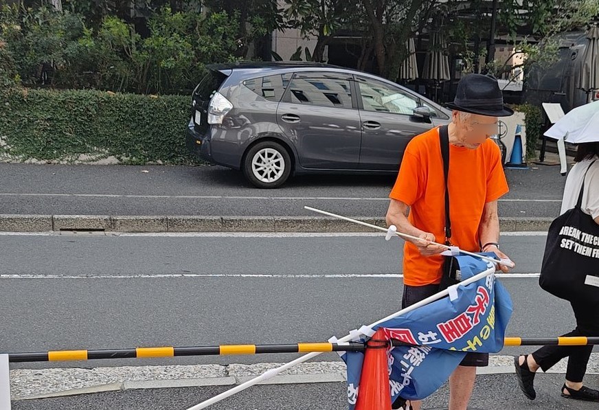 （しぶしぶ旗を畳むご老人）