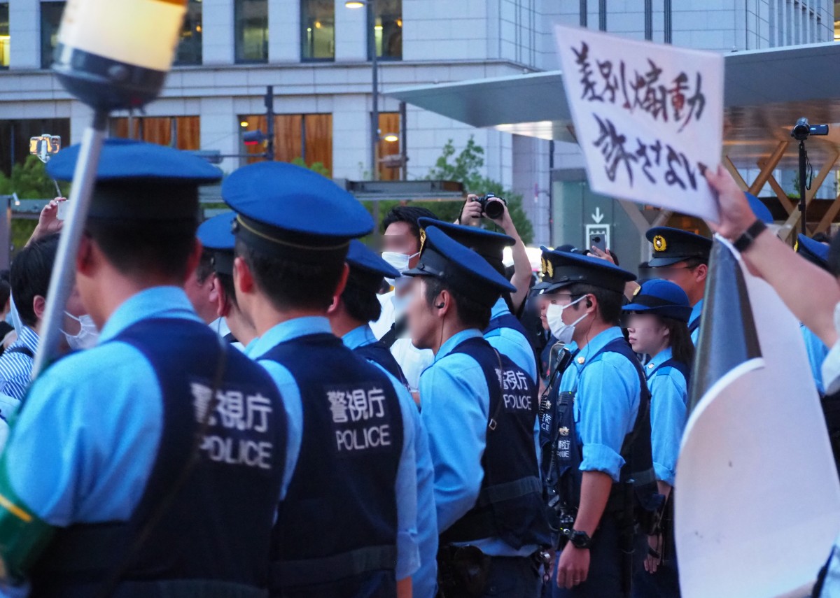 (聴衆の襲撃からプラカードの抗議部隊を守る警官隊)