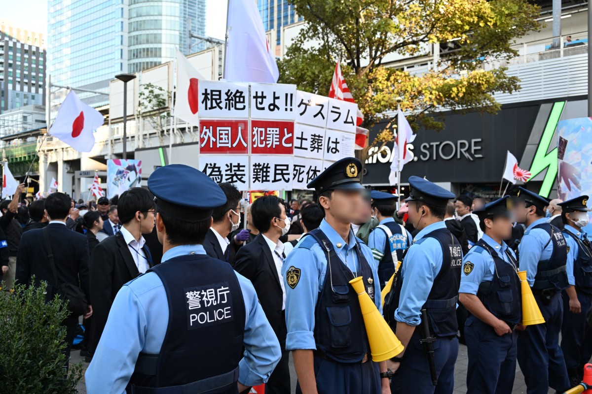 (囲いの後方に並ぶ警官ら)