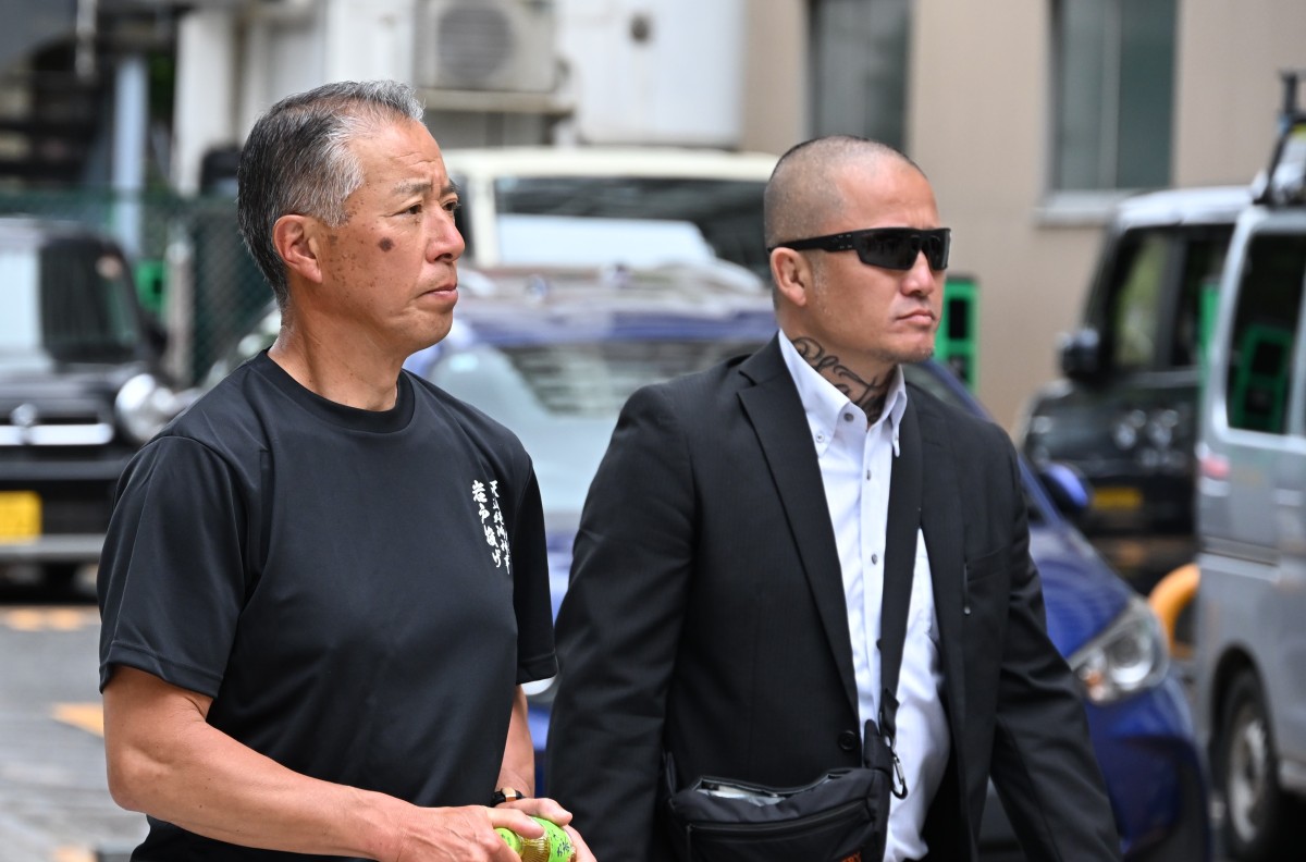 （護衛らしき男性を連れて会場を引き揚げる荒谷卓）