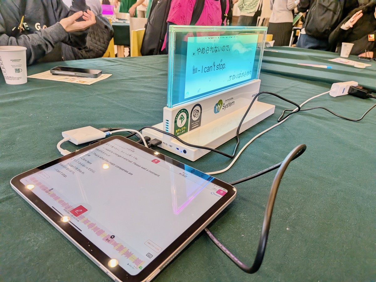 タブレットに打ち込んだ文字が表示される透明ディスプレイ。タブレットからコードで接続されており、アクリルのような透明な板に文字が表示されている