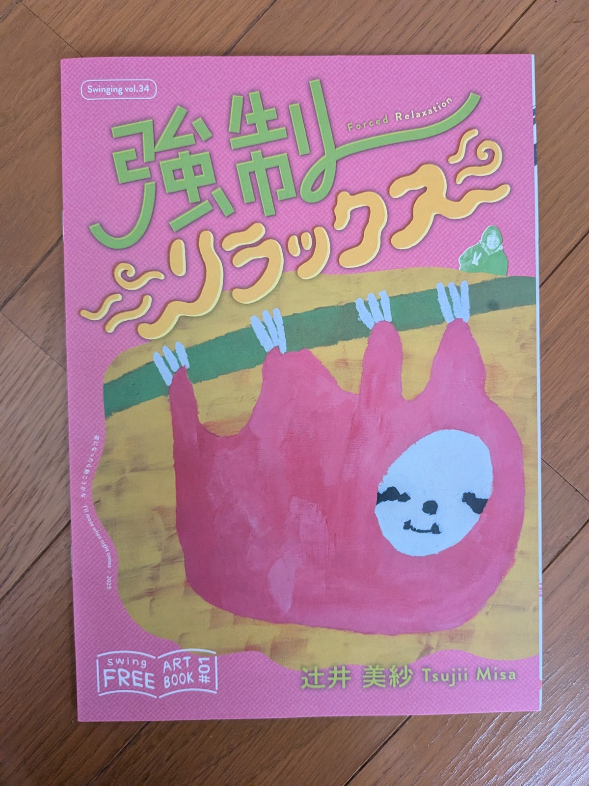 フリーペーパーの表紙。強制リラックスと題字が打たれている。ピンクのナマケモノがぶらさがっている絵画がのっている