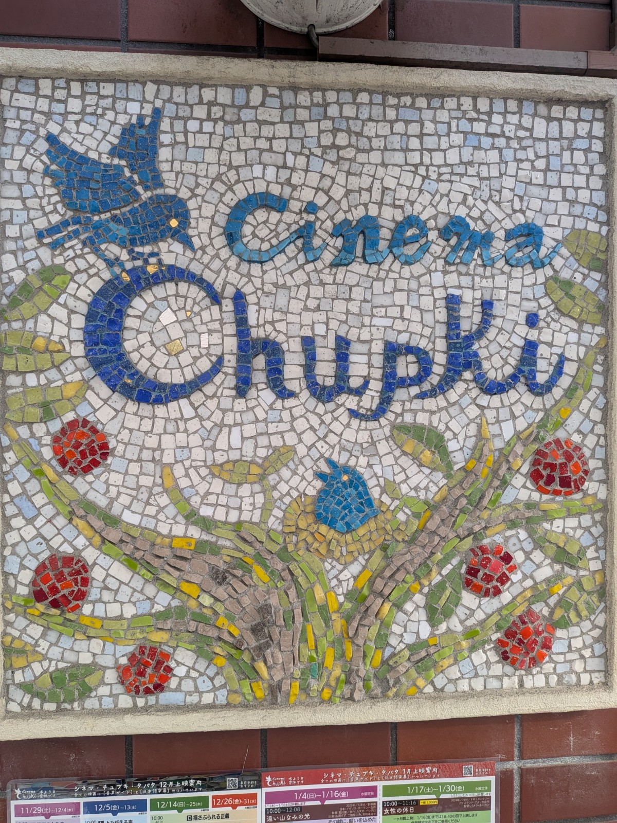 チュプキのモザイク絵。タイルで描かれている。緑の幹に赤い実と青い鳥が描かれている