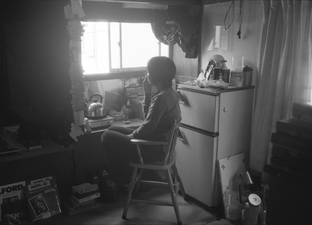 自室の窓から外を眺めている紀子さんを徹さんが後ろから撮った写真(小池紀子さん提供)