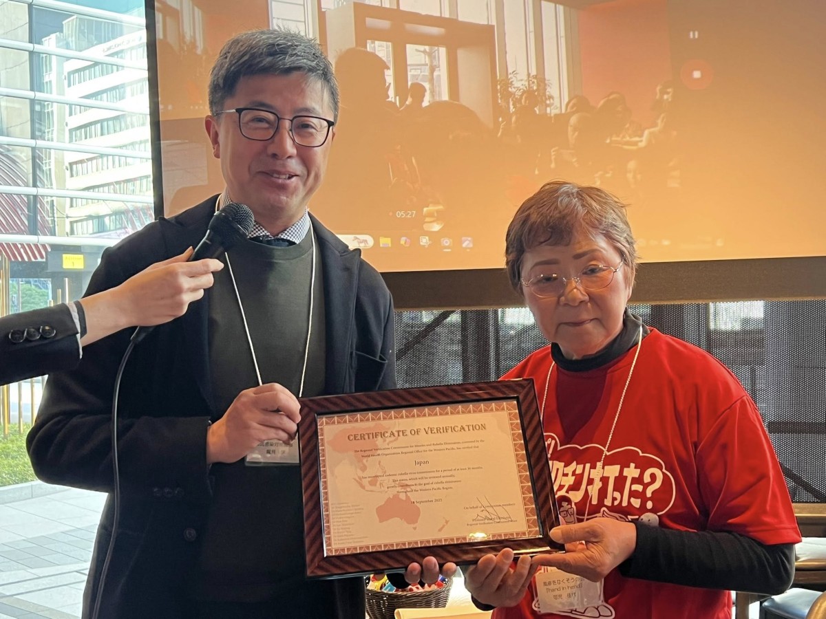 風疹排除の認定証を厚生労働省感染症対策部長の鷲見学さんから手渡される可児佳代さん