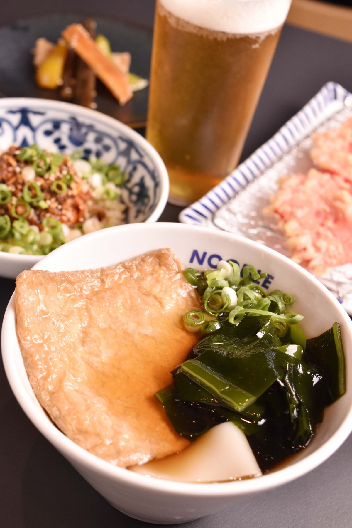クラフトビールや日本酒、ワイン、焼酎などアルコールの種類もバラエティ豊か。あれこれつまんでから〆できしめん、もいい。写真のきしめんは赤つゆに油揚げとわかめをトッピングした高砂980円