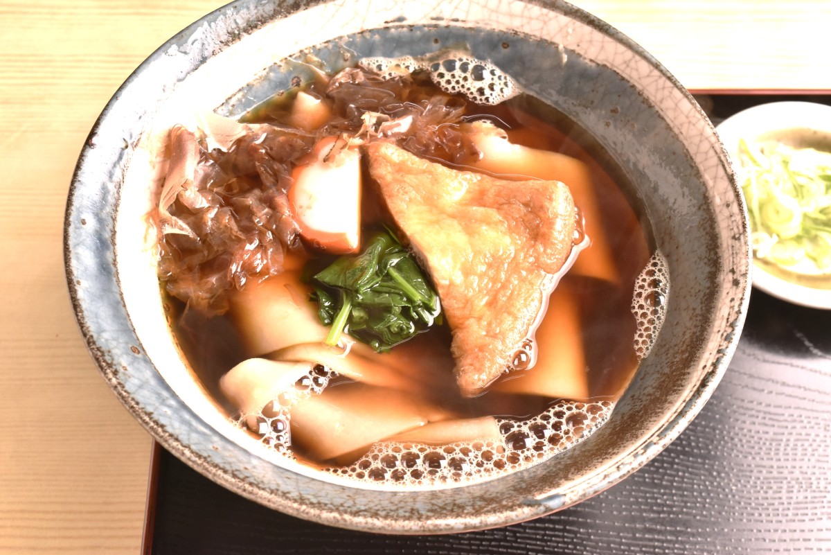 きしめん700円。超幅広の麺から変わり種と思ってしまいがちだが、ふちの赤い名古屋かまぼこ、油揚げ、ほうれん草、かつおぶしの具の取り合わせはきしめんの王道