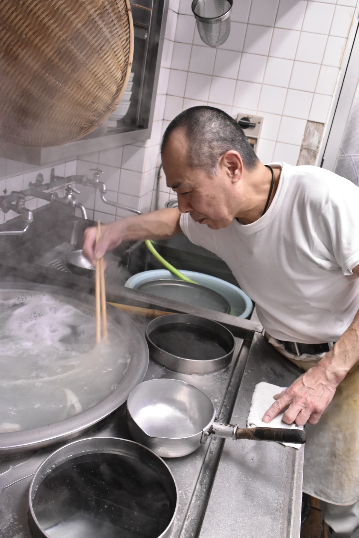 きしめんは釜の中でくっつきやすいのでゆでる際も目が離せない。写真は3代目の渡邊一弘さん。息子の凌さんとともに父子で厨房を守っている