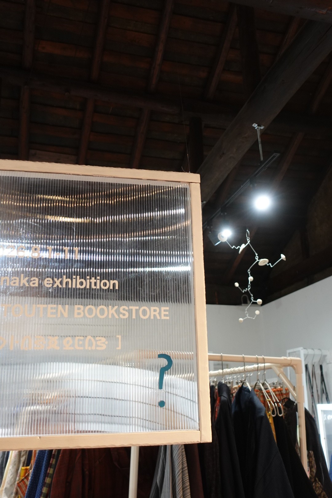 展示の入り口の写真。手作りの看板の奥に衣服が並ぶ。