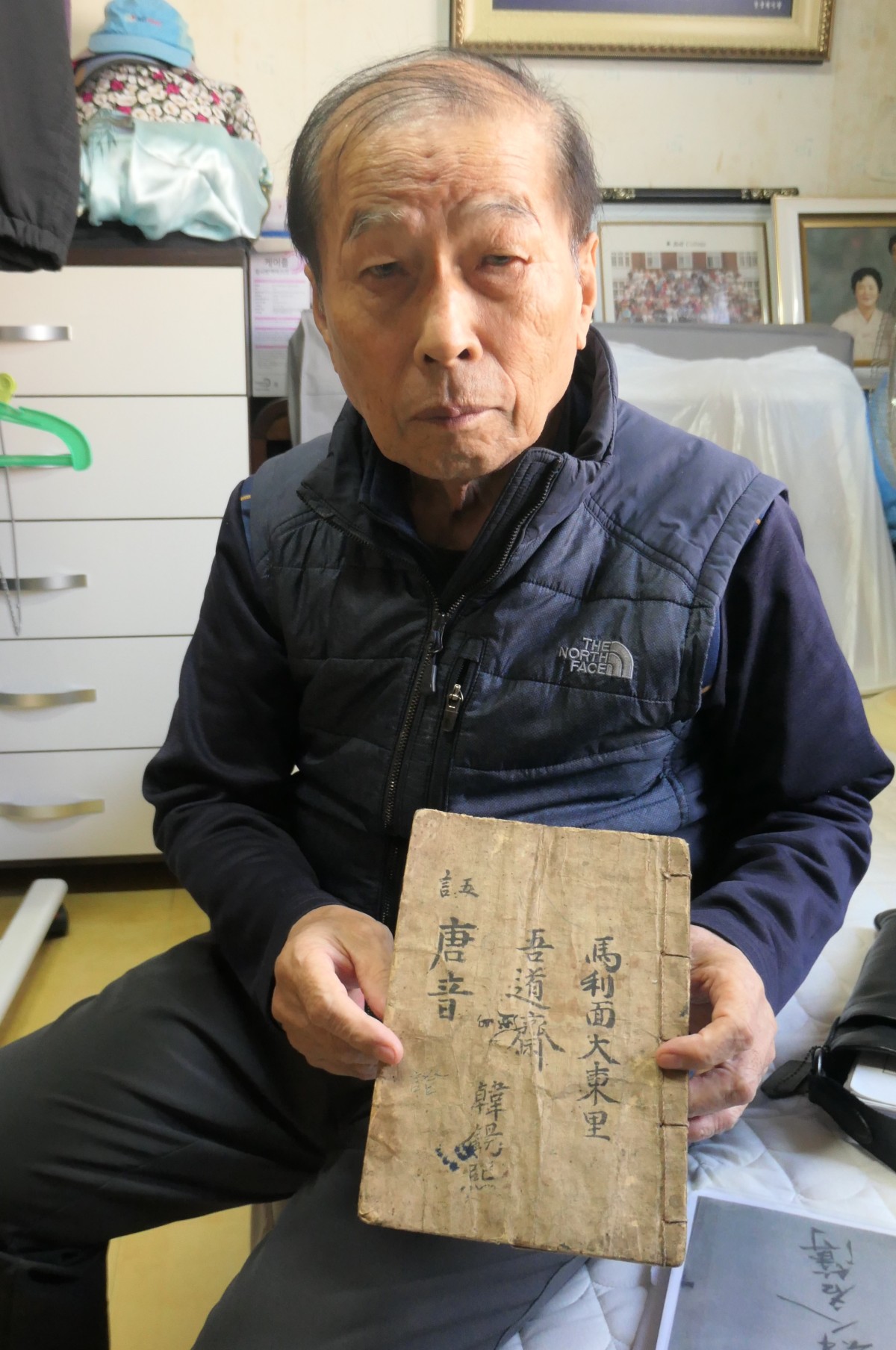 父・ソクヒさんの形見を手にする遺族団体代表のハン・ヨンヨンさん＝2024年11月、慶尚南道・居昌郡にあるハン氏の自宅で（筆者撮影）